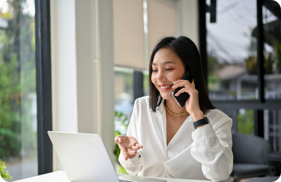an office lady speaking on the phone and using her laptop
